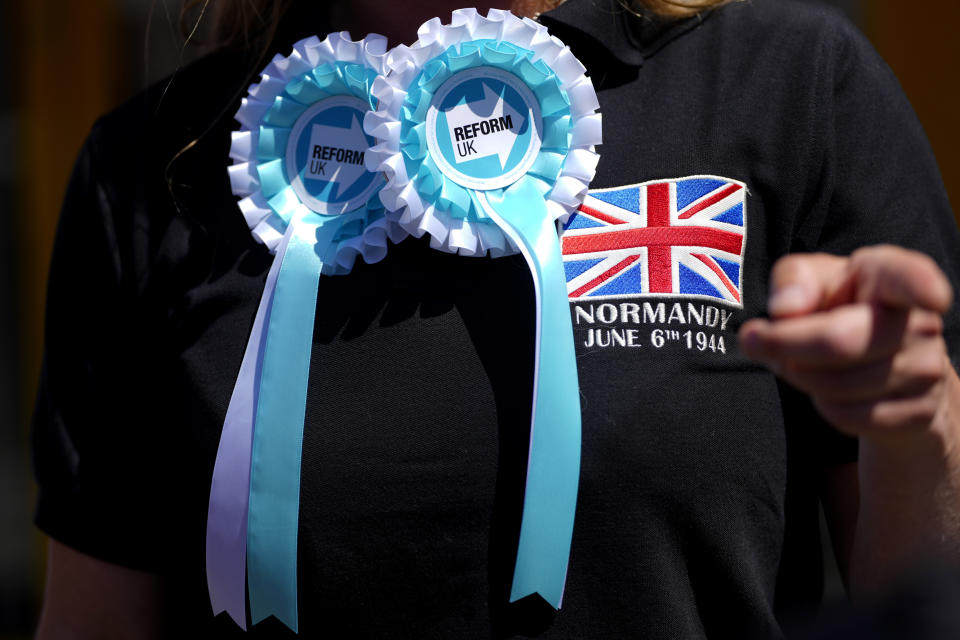 A Reform UK party supporter wears rosettes outside the party office in Clacton-On-Sea, England, Friday, June 21, 2024. Britain votes in a national election next week at a time of high public dissatisfaction over a host of issues. Many Conservative voters are turning away from the governing party, and some are switching to anti-immigration Reform. (AP Photo/Kirsty Wigglesworth)
