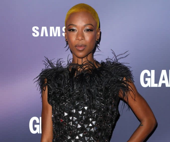 Samira Wiley in a black textured dress with feather accents on the shoulders, posing at an event