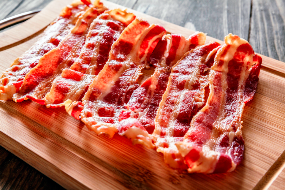 Seven pieces of bacon on a cutting board 