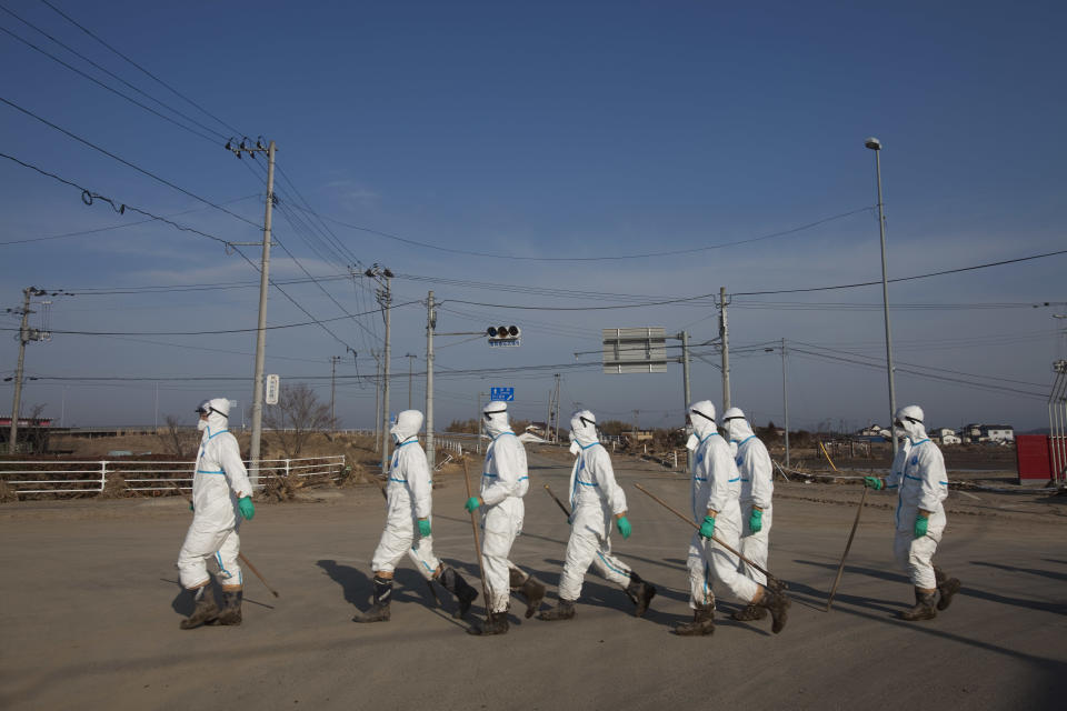 FILE - In this April 7, 2011 file photo, Japanese police wearing protective radiation suits search for the bodies of victims of the tsunami in the Odaka area of Minami Soma, inside the deserted evacuation zone established for the 20-kilometer radius around the Fukushima Dai-ichi nuclear power plants. Japanese film director Yojyu Matsubayashi took a more standard documentary approach for his “Fukushima: Memories of the Lost Landscape,” interviewing people who were displaced in the Fukushima town of Minami Soma. He followed them into temporary shelters in cluttered gymnasiums and accompanied their harried visits to abandoned homes with the gentle patience of a video-journalist. The March 2011 catastrophe in Japan has set off a flurry of independent films telling the stories of regular people who became overnight victims, stories the creators feel are being ignored by mainstream media and often silenced by the authorities. (AP Photo/David Guttenfelder, File)