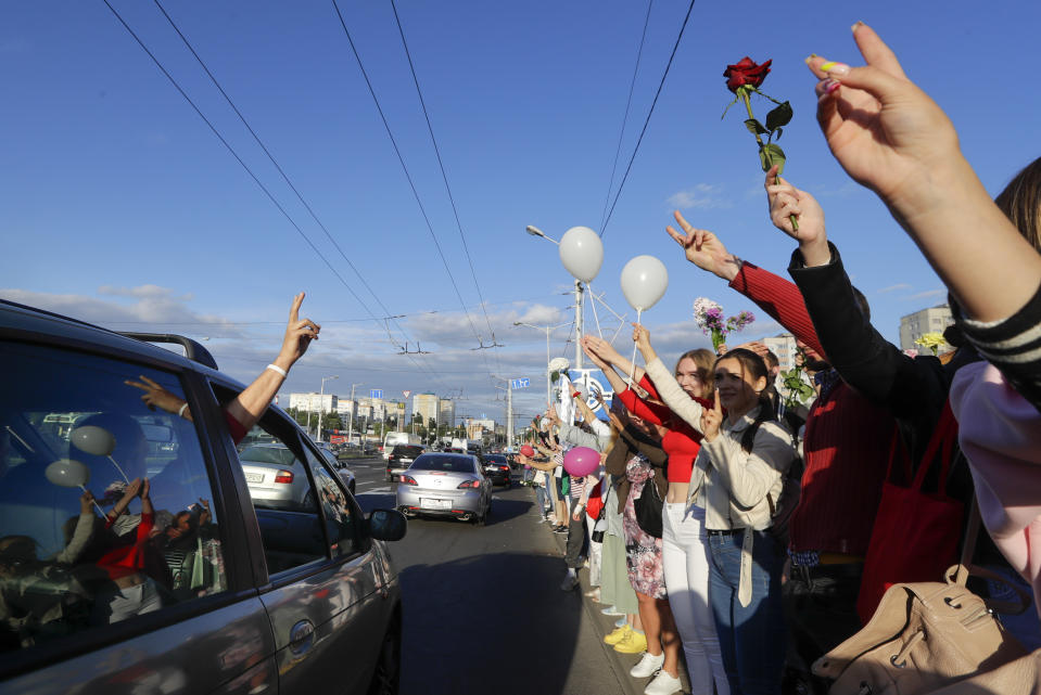 People greet each other waving flowers and white balloons as they gather to protest against the results of the country's presidential election in Minsk, Belarus, Thursday, Aug. 13, 2020. Crowds of protesters in Belarus swarmed the streets and thousands of workers rallied outside industrial plants to denounce a police crackdown on demonstrations over a disputed election that extended the 26-year rule of authoritarian President Alexander Lukashenko. (AP Photo/Sergei Grits)
