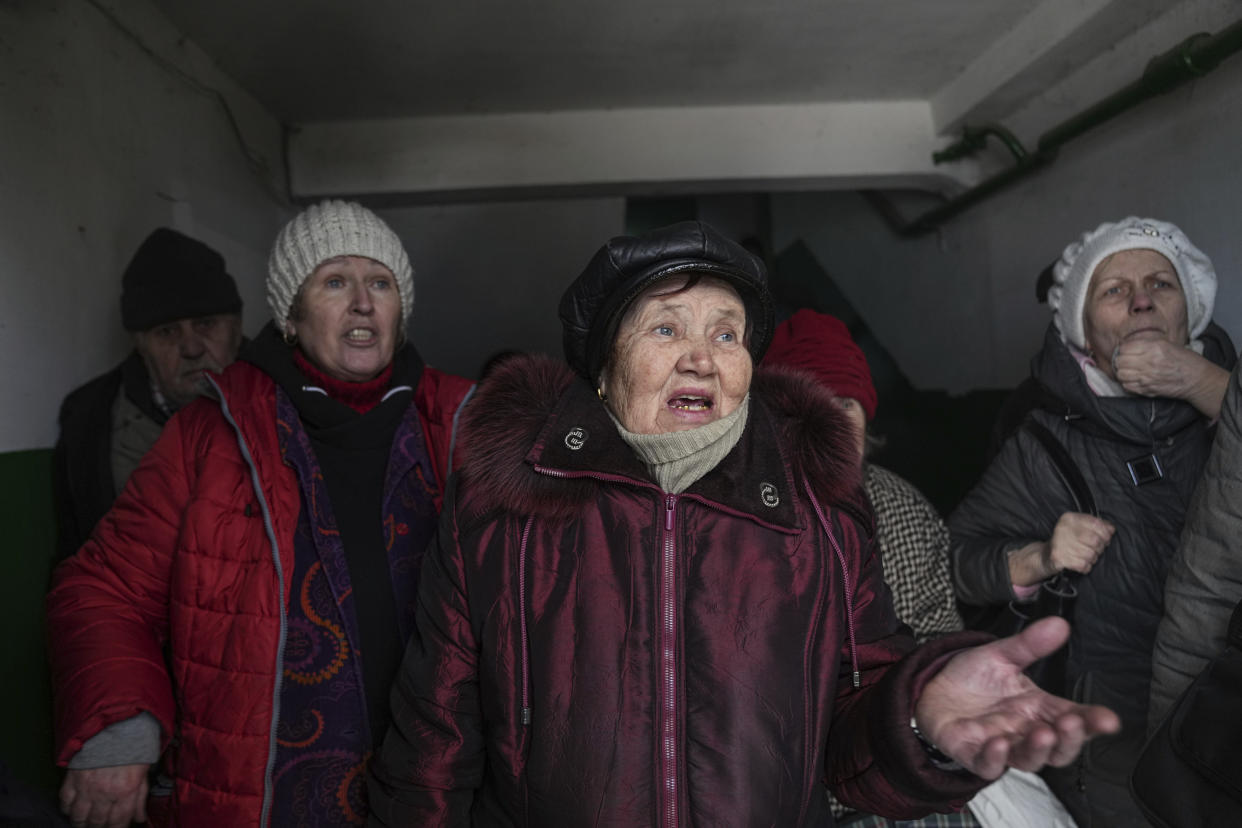 Women talk as they take shelter inside an entryway to an apartment building in Mariupol, Ukraine, Sunday, March 13, 2022. The surrounded southern city of Mariupol, where the war has produced some of the greatest human suffering, remained cut off despite earlier talks on creating aid or evacuation convoys. (AP Photo/Evgeniy Maloletka)