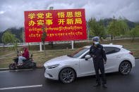 A police officer directs traffic near a billboard that reads in Chinese "Study Communist Party history, understand its theories, do practical work, and make new advances" in Nyingchi in western China's Tibet Autonomous Region, as seen during a rare government-led tour of the region for foreign journalists, Friday, June 4, 2021. Long defined by its Buddhist culture, Tibet is facing a push for assimilation and political orthodoxy under China's ruling Communist Party. (AP Photo/Mark Schiefelbein)