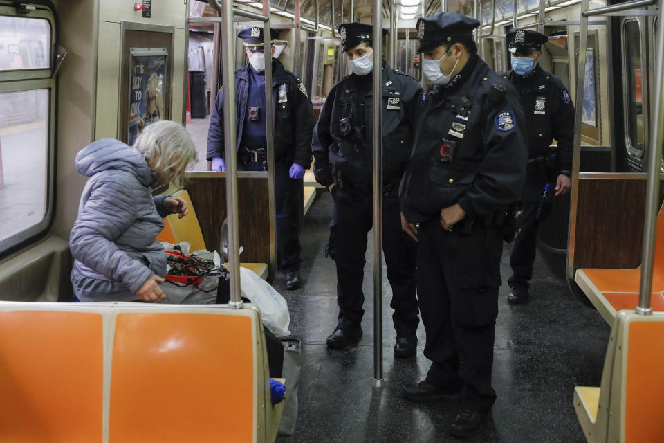 NYPD officers wake up sleeping passengers and direct them to the exits at the 207th Street A-train station, Thursday, April 30, 2020, in the Manhattan borough of New York. (AP Photo/John Minchillo)