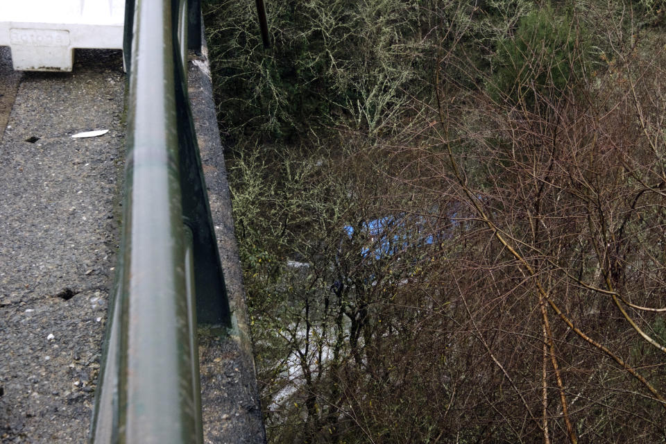 Part of a blue bus is seen after it plunged into a river near Pontevedra in northwestern Spain, Sunday, Dec. 25, 2022. Authorities say rescuers have recovered the victims from the bus that ran off a bridge and plunged into the river on Christmas Eve, killing six passengers and injuring the driver and another passenger. The Spanish Guardia Civil says a total of eight people were on the bus. The two survivors were rescued Saturday night and taken to hospitals. The bodies of the dead were retrieved Sunday. (Cesar Arxina/Europa Press via AP)