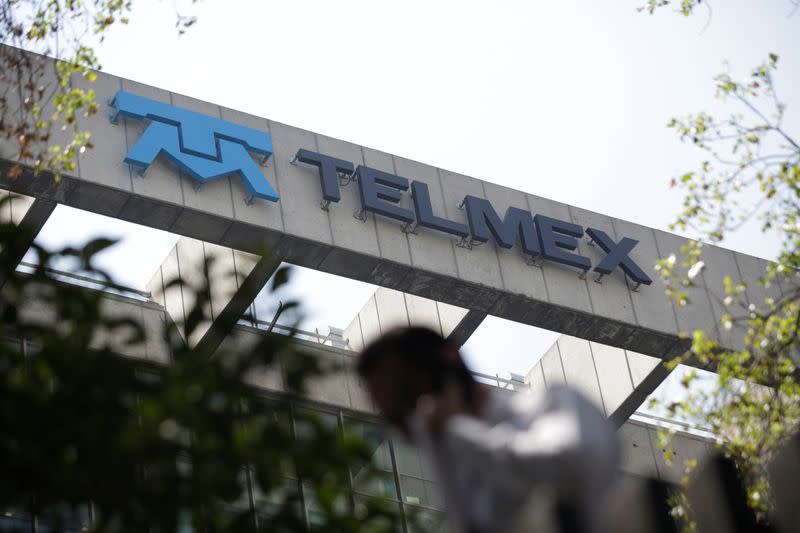 FILE PHOTO: A man crosses a pedestrian bridge near the headquarters of internet and fixed-line phone company Telmex in Mexico City