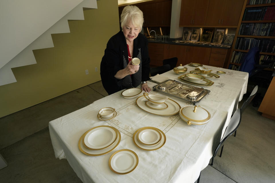 Diane Capone looks over one of the pieces of a china set that once belonged to her grandparents, Mae and Al Capone, on display at Witherell's Auction House in Sacramento, Calif., Wednesday, Aug. 25, 2021. The granddaughter of the famous mob boss and her two surviving sisters will sell 174 family heirlooms at an Oct. 8 auction titled "A Century of Notoriety: The Estate of Al Capone, that will be held by Witherell's in Sacramento. (AP Photo/Rich Pedroncelli)