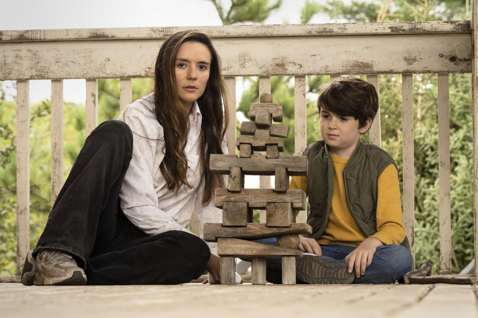 Catalina Sandino Moreno sits with a young boy by a bizarre formation of stones