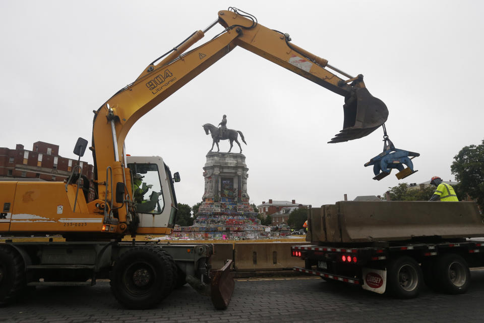 Workers for The Virginia Department of General Services install concrete barriers around the statue of Confederate General Robert E. Lee on Monument Avenue Wednesday, June 17, 2020, in Richmond, Va. The barriers are intended to protect the safety of demonstrators as well as the structure itself. (AP Photo/Steve Helber)