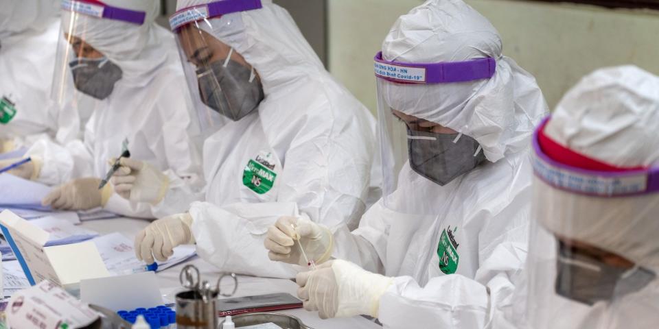 Medical specialists in protective suits work on blood samples collected for a coronavirus (COVID-19) rapid test from people who recently returned from Da Nang City on July 31, 2020 in Hanoi, Vietnam.