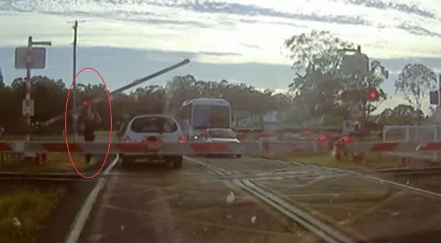 The quick-thinking officer ducked under the first boom gate and forced the second up, allowing the woman to drive off before the train approached. Picture: Queensland Police