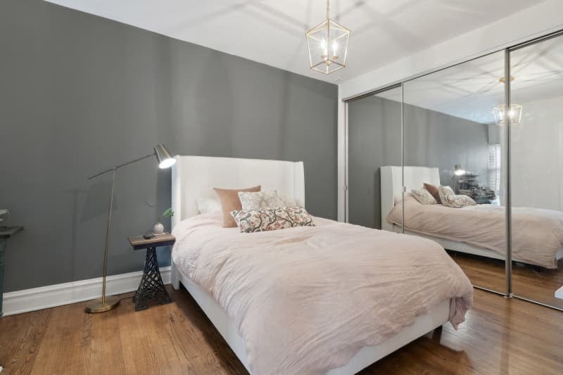 Bedroom with gray accent wall and white bed with pale blush linens