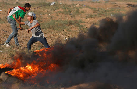 A Palestinian boy hurls stones at Israeli troops during a protest calling for lifting the Israeli blockade on Gaza and demanding the right to return to their homeland, at the Israel-Gaza border fence, east of Gaza City September 14, 2018. REUTERS/Mohammed Salem