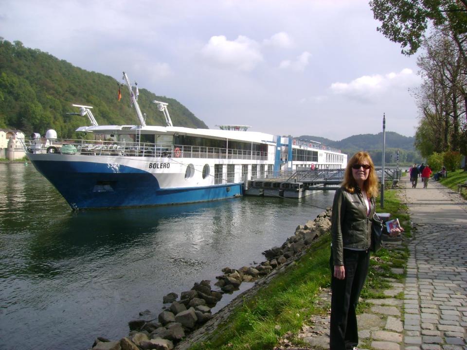 This 2012 photo shows Betty Adams in Passau, Germany, with the MS Bolero, a Viking River Cruises ship. Adams took a cruise on the Danube River with her husband Glenn Adams but the couple missed a connection with a flight en route to the first departure port. They took a next-day flight and managed to get to the ship in time, but they were glad to have travel insurance to cover costs associated with the scrambled plans. Many travel experts recommend insurance for complicated itineraries, including cruises. (AP Photo/Glenn Adams)