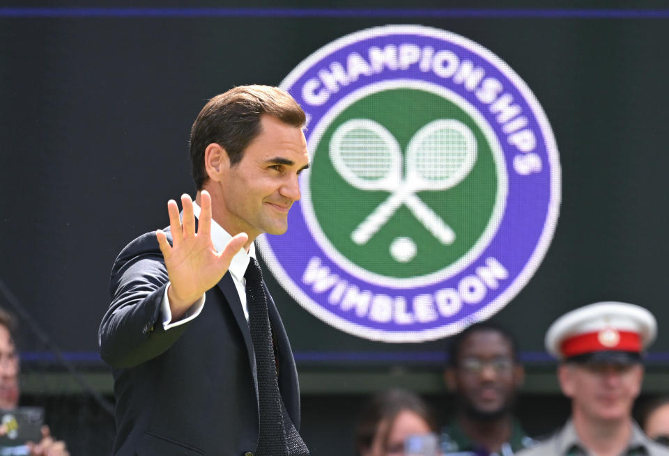 Roger Federer walks past the Wimbledon logo.