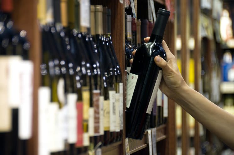 A woman's hand reaches out to select a bottle of red wine from the shelf of a wine shop. (Photo: AFP)