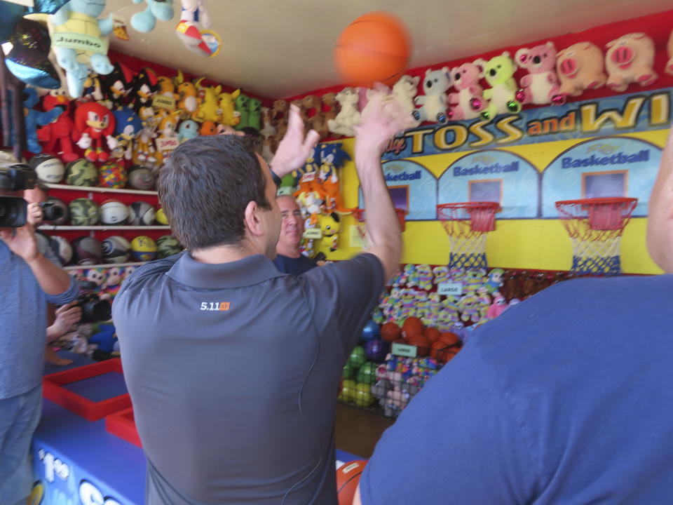 New Jersey Attorney General Matthew Platkin shoots a basketball at a hoop on the Seaside Heights, N.J., boardwalk, Friday, May 31, 2024 during an event to inspect boardwalk games of chance. Later that day, Platkin blamed the city of Wildwood, N.J., for not assigning enough police officers to patrol its boardwalk over the Memorial Day weekend when crowds of rowdy teens and young adults overwhelmed the city's capability to respond to disturbances, forcing the boardwalk to be shut down overnight on Sunday, May 26. (AP Photo/Wayne Parry)