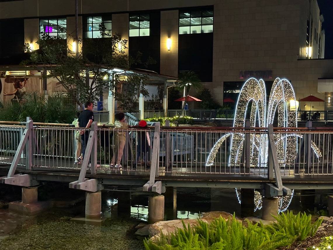 Families overlook the new Life Time resort-style gym and holiday decorations from a bridge at The Falls mall on a Saturday night, Nov. 25, 2023.