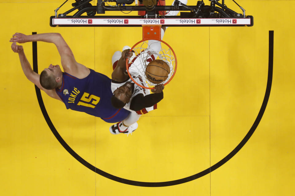 Miami Heat center Bam Adebayo dunks against Denver Nuggets center Nikola Jokic (15) during the first half of Game 3 of basketball's NBA Finals, Wednesday, June 7, 2023, in Miami. (Mike Ehrmann/Pool Photo via AP)