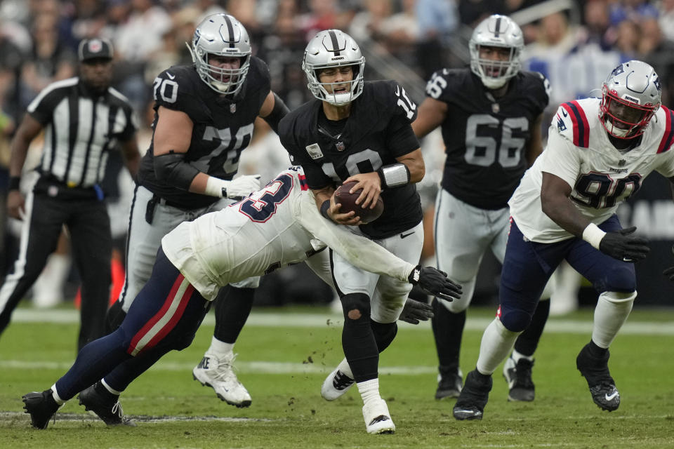 Las Vegas Raiders quarterback Jimmy Garoppolo, center, is hauled down by New England Patriots linebacker Anfernee Jennings during the first half of an NFL football game Sunday, Oct. 15, 2023, in Las Vegas. (AP Photo/John Locher)