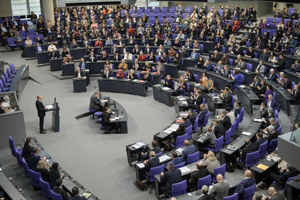 German Chancellor Olaf Scholz, at the podium left, delivers a speech about Germany's budget crisis at the parliament Bundestag in Berlin, Germany, Tuesday, Nov. 28, 2023. With its economy already struggling, Germany now is wrestling to find a way out of a budget crisis after a court struck down billions in funding for clean energy projects and help for people facing high energy bills because of Russia's war in Ukraine. (AP Photo/Markus Schreiber)