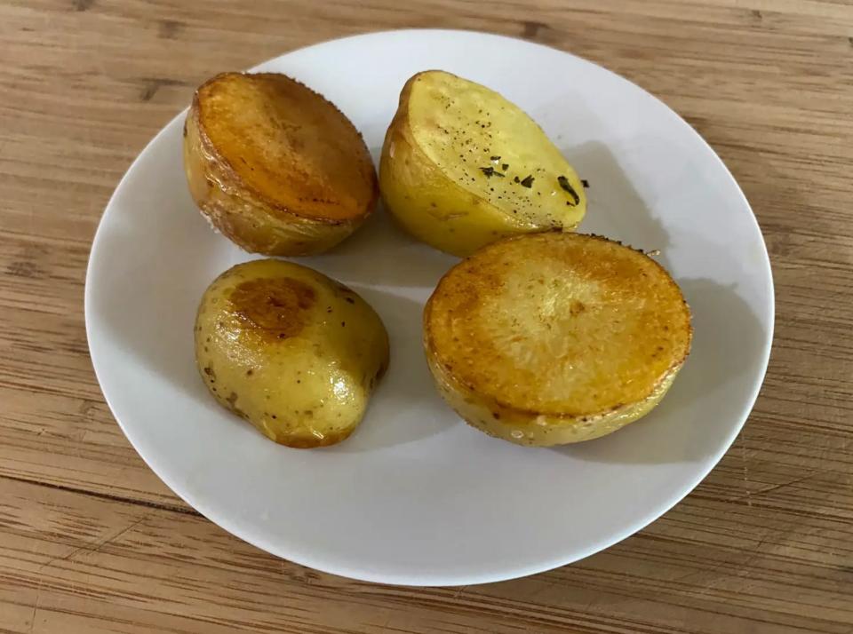 four golden brown roasted potato halves on a white plate