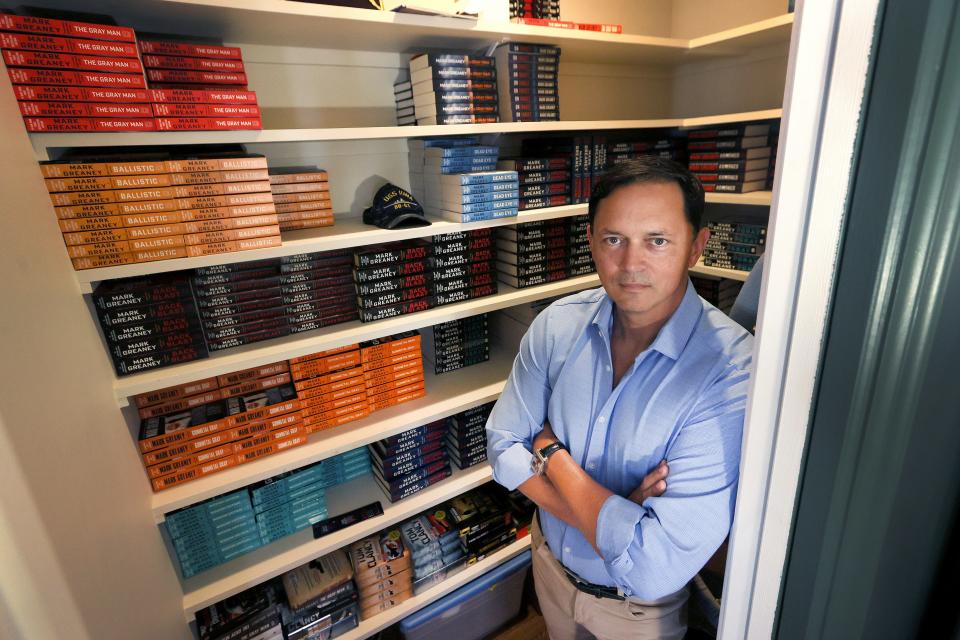 Best-selling author Mark Greaney, best known for his 'Gray Man' spy series poses in front of a closet filled with his books at his East Memphis home on Friday, June 24, 2022. A movie based on his first 'Gray Man' novel wiill debut on Netflix and in theaters this summer.