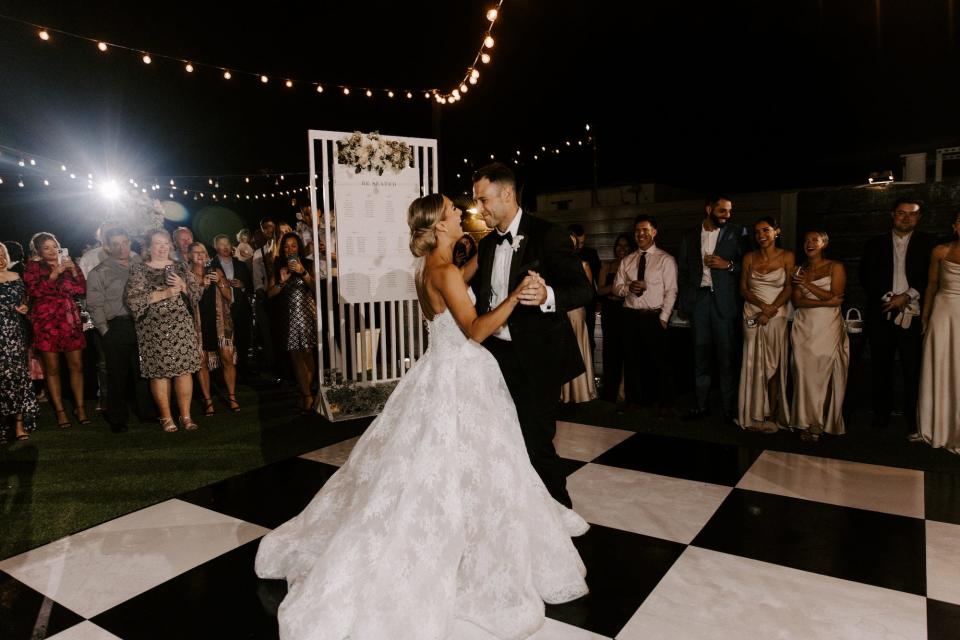 A bride and groom dance during their wedding reception on a black-and-white checkerboard dance floor.