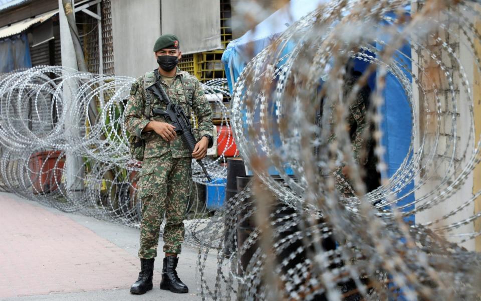 A soldier stands guard outside an area under enhanced lockdown in Kuala Lumpur, Malaysia - Lim Huey Teng/Reuters