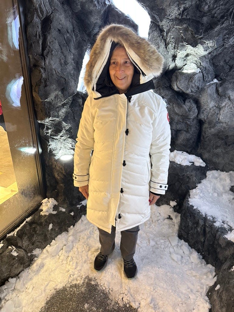A woman wearing a white parka with a fur-trimmed hat.