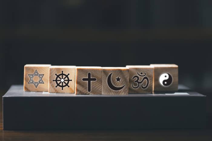 Wooden blocks showing symbols of six religions placed in a row: Judaism, Buddhism, Christianity, Islam, Hinduism, and Taoism