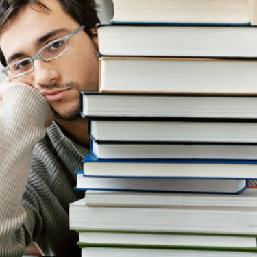 Bored student behind a stack of books web