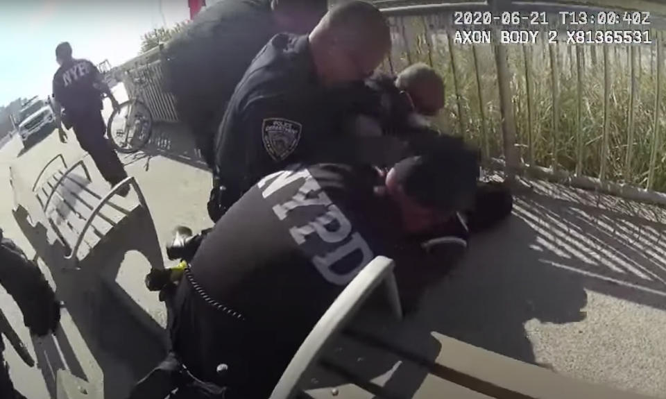 In this photo taken from police body cam video, New York Police officers arrest a man on a boardwalk Sunday, June 21, 2020, in New York. The NYPD says officer David Afanador was arrested Thursday on charges of strangulation and attempted strangulation over the incident last weekend on the Rockaway Beach boardwalk. Video showed Afanador with his arm wrapped around a man’s neck for several seconds during an arrest. (NYPD via AP)