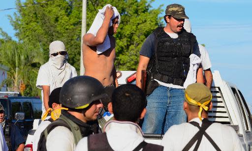 Miembros de un grupo de autodefensas mexicano vigilan a un supuesto integrante del cartel Los Caballeros Templarios frente al Palacio Municial en la comunidad de Nueva Italia, en Michoacán, el 12 de enero de 2014 (AFP | Alfredo Estrella)