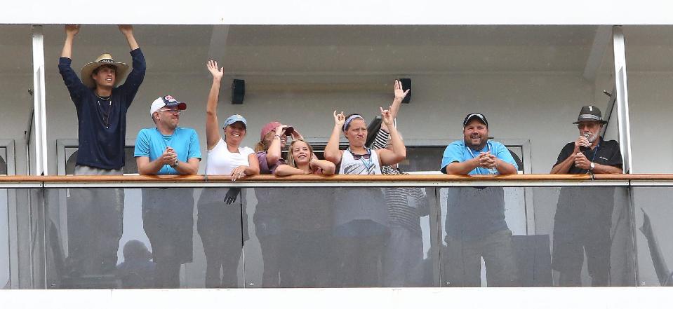 Passengers wave and cheer from the Carnival Conquest cruise ship as the vessel arrives at the Alabama Cruise Terminal on the Mobile River on a rainy Sunday, July 7, 2013, in downtown Mobile, Ala. The Conquest was diverted from New Orleans to Mobile after a tugboat sank in the Mississippi River Saturday, closing the river. (AP Photo/AL.com, Mike Brantley)