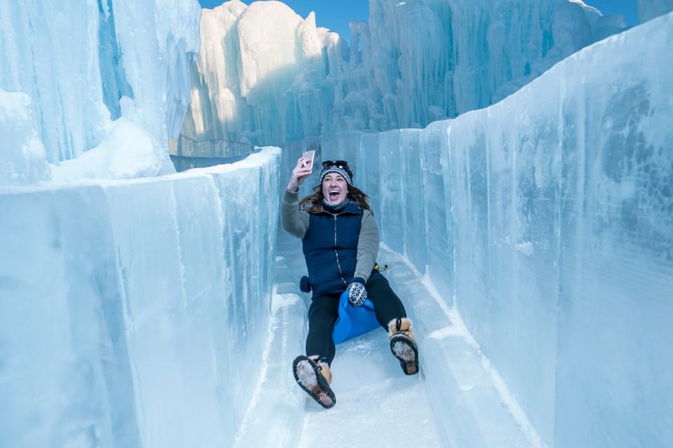 An Ice Castles visitor slips their way down an ice slide.