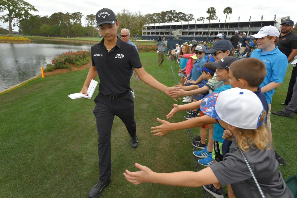 Min Woo Lee slaps palms with children between the 16th green and the 17th tee of the Players Stadium Course at TPC Sawgrass on Thursday during the first round of The Players Championship. Lee is among the first-time Players participants.
