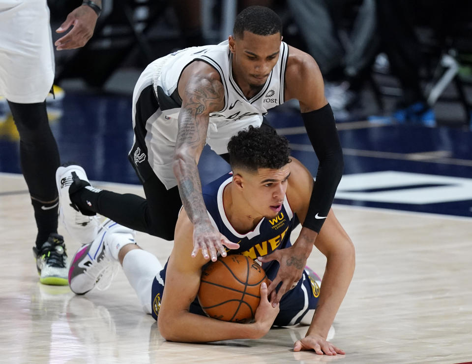 Denver Nuggets forward Michael Porter Jr., bottom, cover the ball as San Antonio Spurs guard Dejounte Murray defends in the first half of an NBA basketball game Friday, April 9, 2021, in Denver. (AP Photo/David Zalubowski)