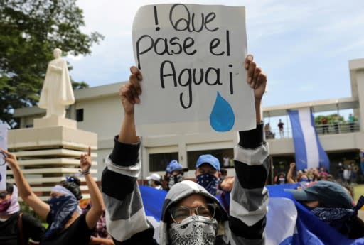 A protester carries a sign reading "Let the water pass" during a demonstration by students and relatives of political prisoners in Managua