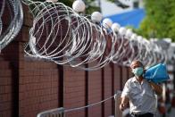 A man walks next to barbwire at the Crown Property Bureau in Bangkok