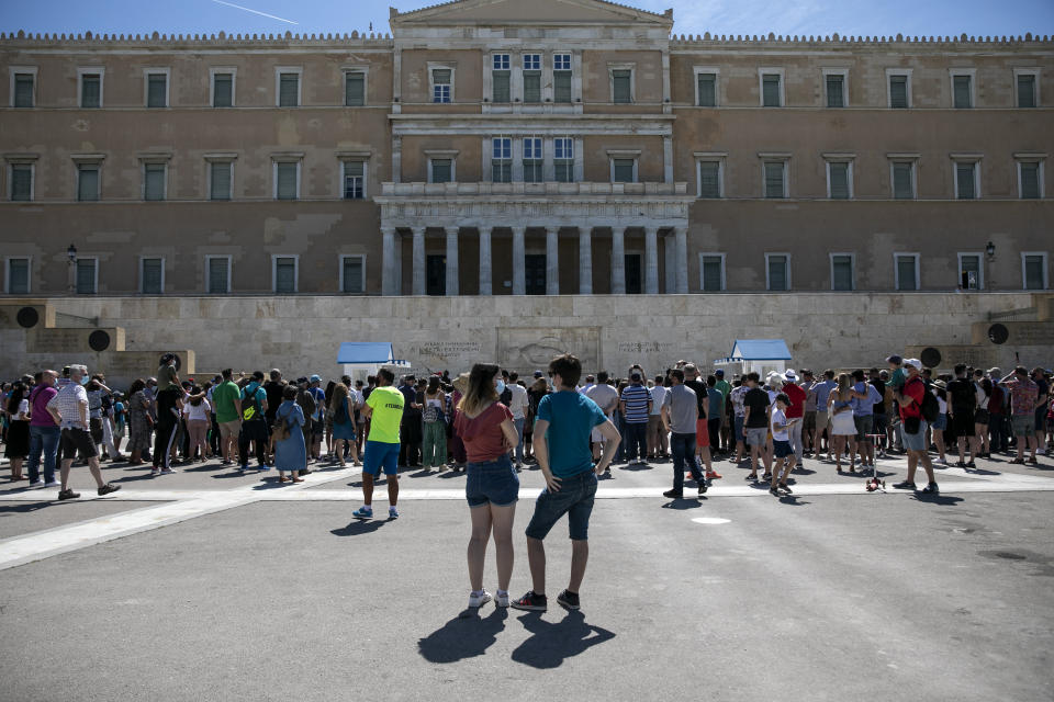 People watch a change of shift of Presidential guards, in Athens, Sunday, May 23, 2021. Greece launched its tourism season last week amid a competitive scramble across the Mediterranean to lure vacationers emerging from lockdowns. (AP Photo/Yorgos Karahalis)