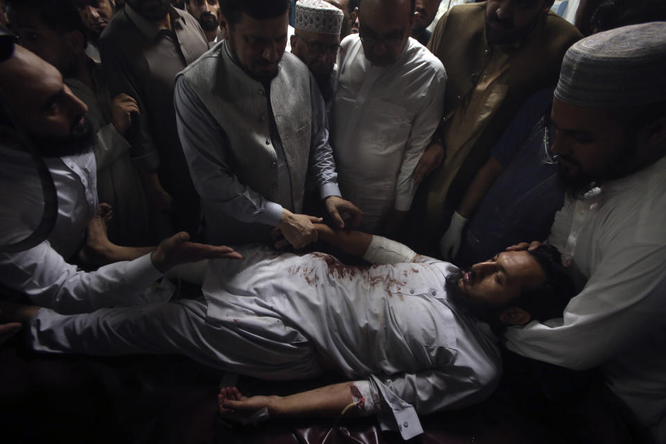 Relatives of an injured victim of a powerful bomb stand around his bed at a hospital in Peshawar, Pakistan, Sunday, July 30, 2023. A bomb ripped through a rally by supporters of a hard-line cleric and political leader in the country's northwestern Bajur district that borders Afghanistan on Sunday, police and health officials said. (AP Photo/Muhammad Sajjad)