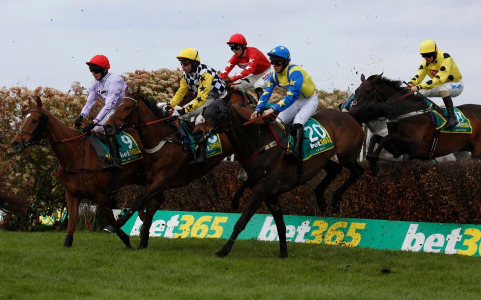 Wayne Hutchinson and Talkischeap (centre, black and white chessboard with yellow sleeves and cap) clear an early fence before going on to win The bet365 Gold Cup at Sandown Park earlier this year - PA