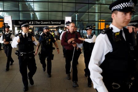 Police officers detain environmental activist James Brown at Heathrow Terminal 2, after climate change protesters tried to launch drones within the airport's exclusion zone, in London