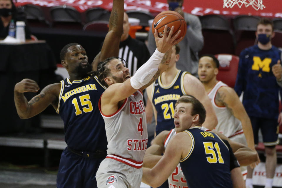 Ohio State's Duane Washington, center, shoots between Michigan's Chaundee Brown, left, and Austin Davis during the first half of an NCAA college basketball game Sunday, Feb. 21, 2021, in Columbus, Ohio. (AP Photo/Jay LaPrete)