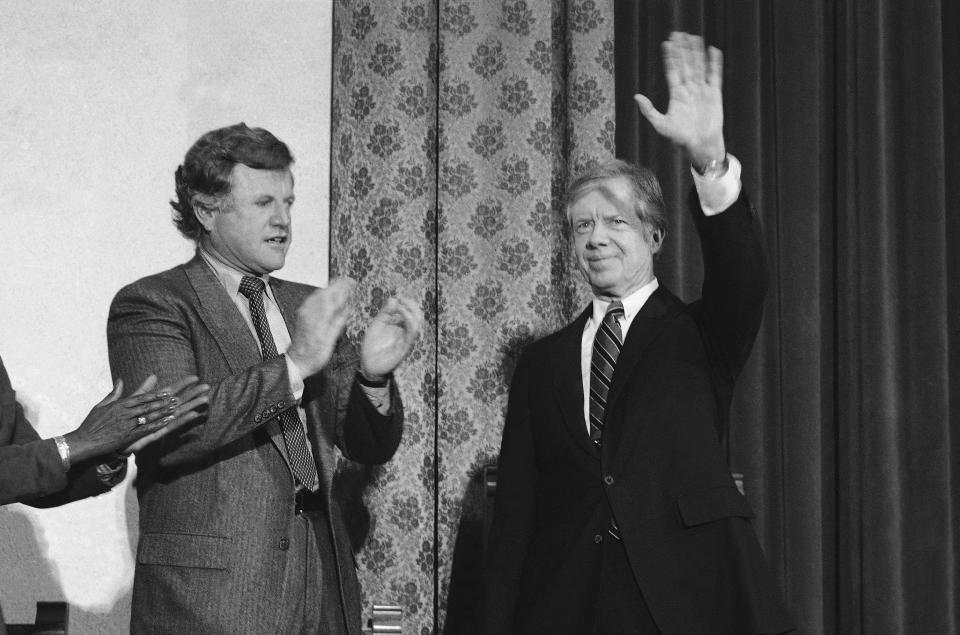 President Jimmy Carter waves as he is applauded by Sen. Edward Kennedy, left, and other supporters during a campaign appearance in Brooklyn in October 1980.