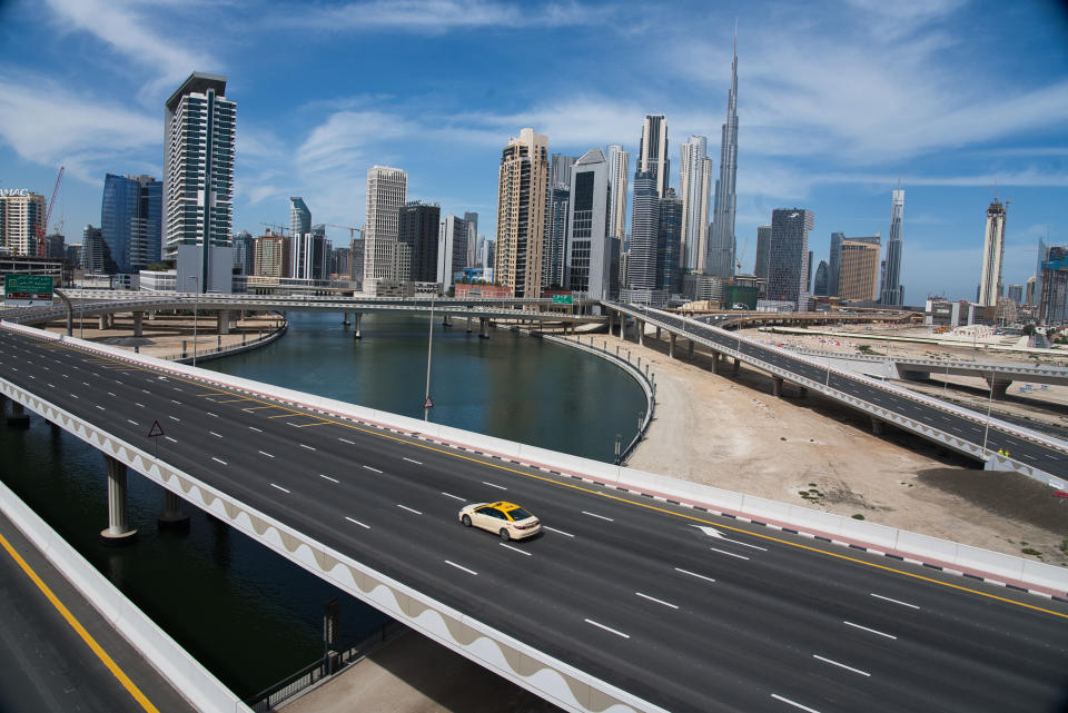 A lone taxi cab drives over a typically gridlocked highway with the Burj Khalifa, the world's tallest building, in the skyline behind it in Dubai, United Arab Emirates, Monday, April 6, 2020. Dubai, one of seven sheikdoms in the United Arab Emirates, is now under a 24-hour lockdown over the new coronavirus pandemic. (AP Photo/Jon Gambrell)