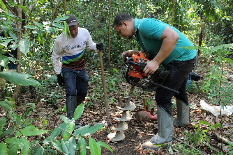 Agronomy engineer Ueliton Pinheiro Januario and Rioterra plant nursery worker Juciney Pinheiro dos Santos dig for soil samples while measuring carbon content on a parcel of Amazon rainforest in Itapua do Oeste
