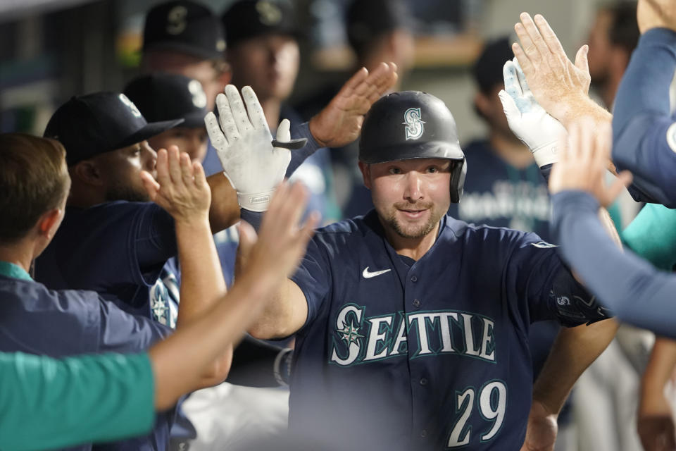 Seattle Mariners' Cal Raleigh is greeted in the dugout after he hit a solo home run against the Texas Rangers during the seventh inning of a baseball game, Tuesday, July 26, 2022, in Seattle. (AP Photo/Ted S. Warren)