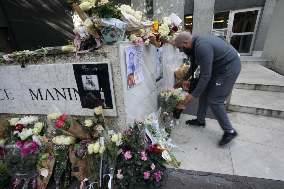 A man lays flowers outside the building where the body of 12-year-old schoolgirl was discovered in a trunk, in Paris, Wednesday, Oct. 19, 2022. France has been "profoundly shaken" by the murder of a 12-year-old schoolgirl, whose body was found in a plastic box, dumped in a courtyard of a building in northeastern Paris, the government spokesman Olivier Veran said on Wednesday. The placard in the center left, reads "Rest in Peace". (AP Photo/Michel Euler)